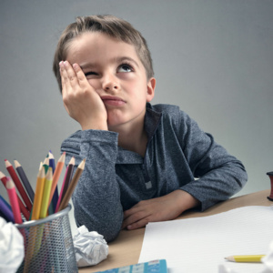 fehlende Motivation zum Lernen? Kind sitzt frustriert an Schreibtisch