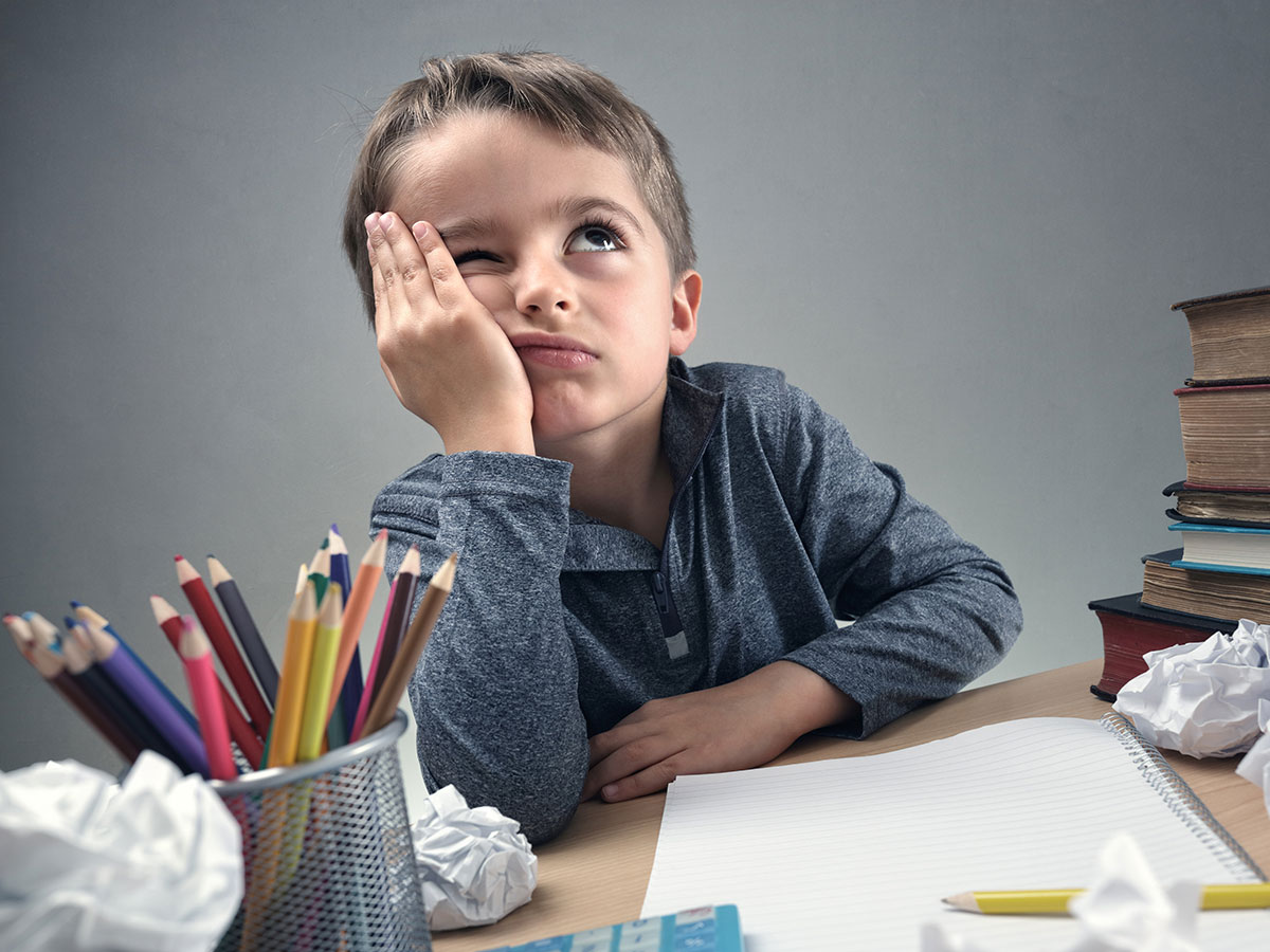 fehlende Motivation zum Lernen? Kind sitzt frustriert an Schreibtisch