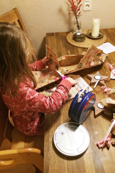 Mädchen packt zur Weihnachtszeit Geschenke aus. 