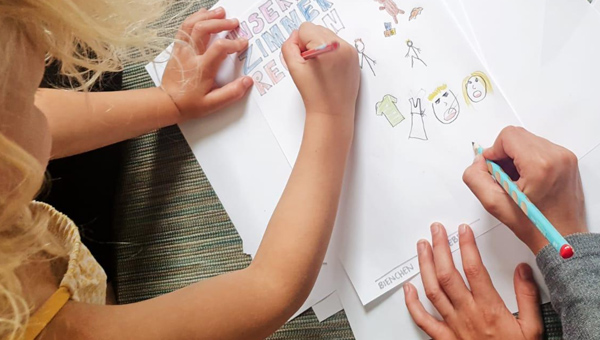 Kinder schreiben gemeinsam die Regeln des Zusammenlebens im Geschwisterzimmer auf