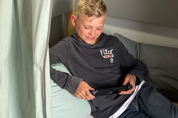 Junge spielt am Tablet im Etagenbett Sten