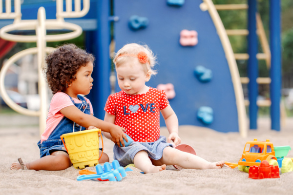 Kinder spielen auf dem Spielplatz und lernen soziales Verhalten.