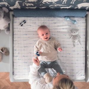 Baby liegt auf Wickelkommode und lacht glücklich.