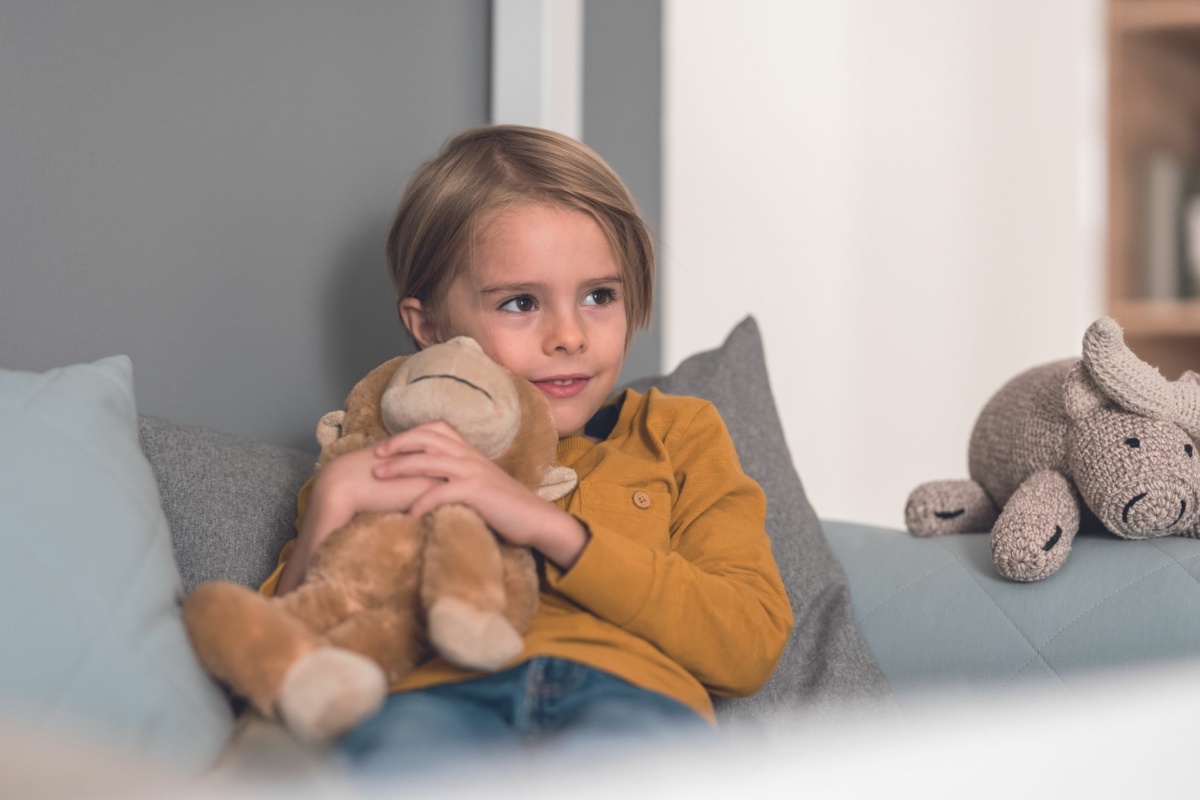 Kleiner Junge kuschelt mit Kuscheltier im PAIDI-Bett