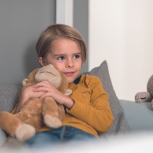 Kleiner Junge kuschelt mit Kuscheltier im PAIDI-Bett